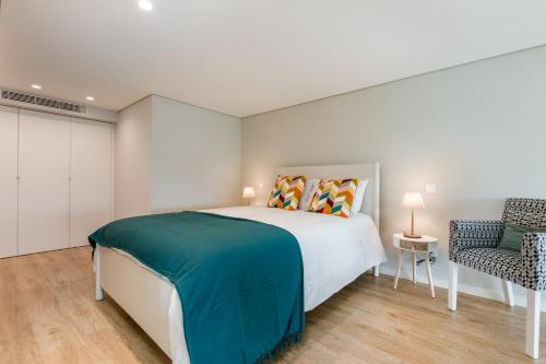 a bedroom with a large bed and a chair at Douro Tower Loft - Shared Pool in Vila Nova de Gaia