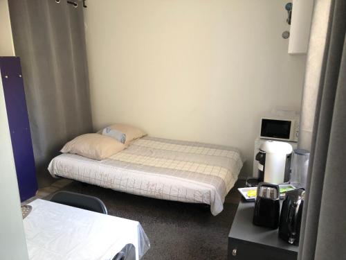 une petite chambre avec un lit et une télévision dans l'établissement Jungle Art Studio Colmar, à Colmar