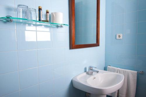 a blue bathroom with a sink and a mirror at Hotel Antiga in Calafell