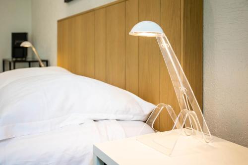 eine weiße Lampe auf einem Tisch neben einem Bett in der Unterkunft les Jardiniers in Straßburg
