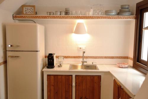 Una cocina con fregadero y refrigerador blanco. en CasArena Agua Amarga, en Agua Amarga