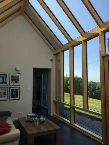 un salon avec une véranda avec de grandes fenêtres dans l'établissement Beautiful villa with pool and stunning sea view, à Quinéville