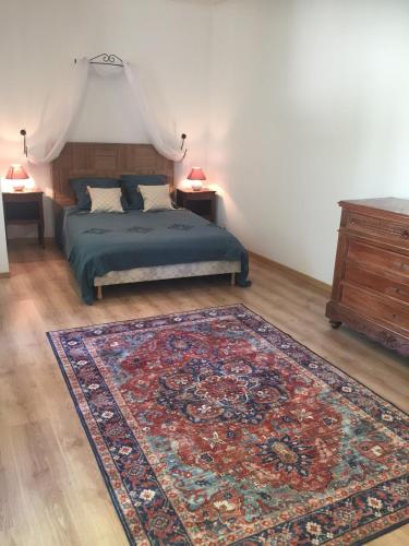 - une chambre avec un lit, un tapis et une commode dans l'établissement Logement Château de Villeneuve, 