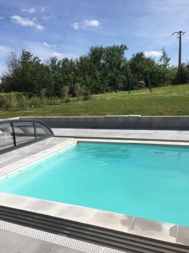 une grande piscine bleue avec un champ en arrière-plan dans l'établissement Beautiful villa with pool and stunning sea view, à Quinéville