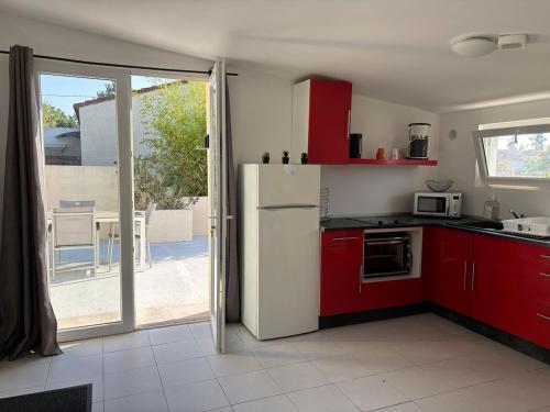 une cuisine avec des armoires rouges et un réfrigérateur blanc dans l'établissement T2 climatisé avec piscine, à Prunelli-di-Fiumorbo