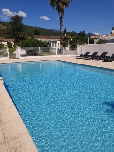 une grande piscine bleue avec des chaises en face d'une maison dans l'établissement T2 climatisé avec piscine, à Prunelli-di-Fiumorbo