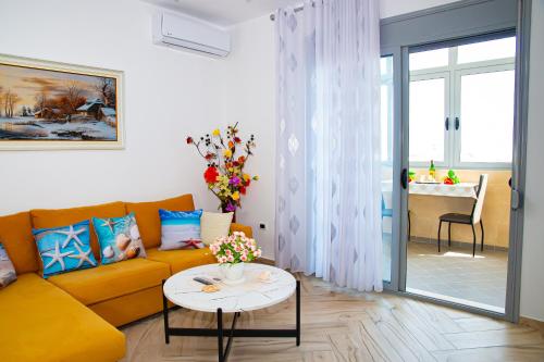 ein Wohnzimmer mit einem gelben Sofa und einem Tisch in der Unterkunft Seashell Apartment in Vlorë