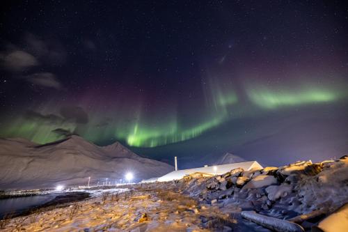 an aurora in the sky over a snow covered mountain at The Sigló House in Siglufjörður
