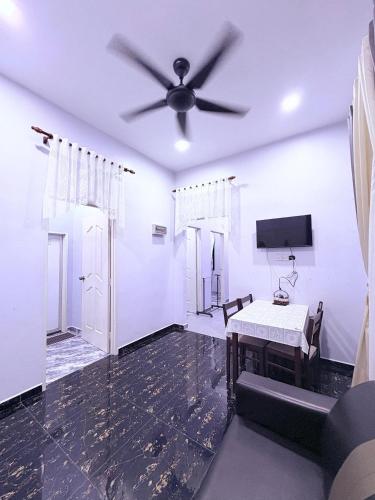 a living room with a ceiling fan and a table at Bushriah Homestay Pendang in Pendang