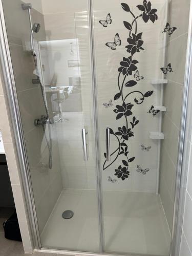 d'une douche avec une porte en verre aux papillons. dans l'établissement T2 500m de la plage Clim parking privé, à Leucate-Plage