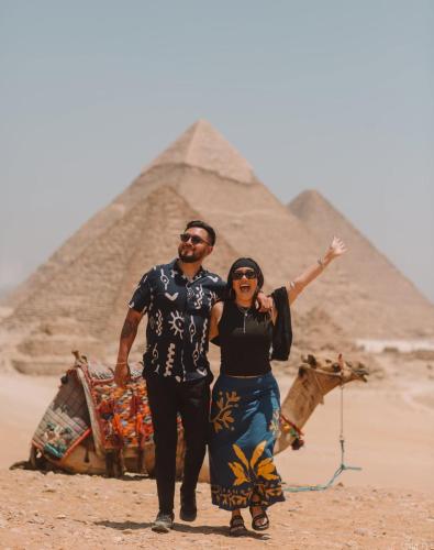 a man and a woman standing in front of the pyramids at Mena Pyramids Hotel in Cairo