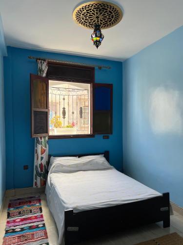 a blue bedroom with a bed and a window at Moroccan Family House in Agadir