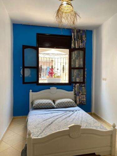 a blue bedroom with a bed with a window at Moroccan Family House in Agadir