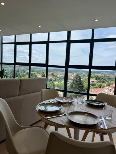 Un comedor con mesa y sillas y una gran ventana. en Apartamentos-loft A Muralla, en Tui