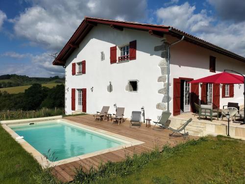 a house with a swimming pool in front of it at Maison basque de charme avec piscine in Souraïde