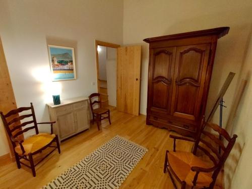 a living room with chairs and a wooden cabinet at Maison basque de charme avec piscine in Souraïde