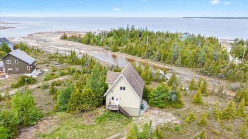 an aerial view of a small house on a hill next to the ocean at Dragonfly Cove - Nature-Inspired Lakeside Living in Tobermory