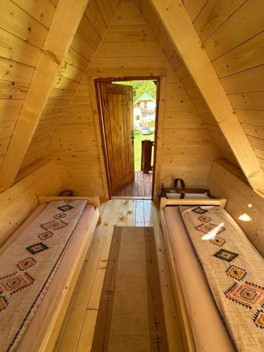two beds in a wooden attic with a doorway at Bungalov Veruša in Podgorica