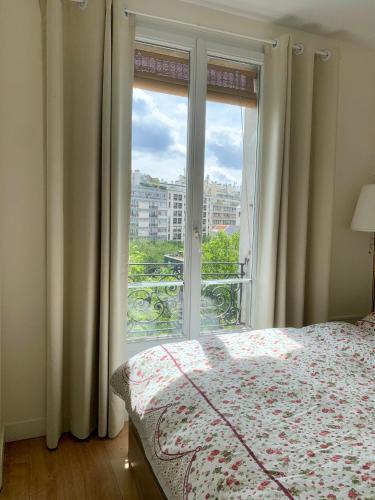une chambre avec un lit et une grande fenêtre dans l'établissement Cozy Frenchy apartment nearby La Seine, à Paris