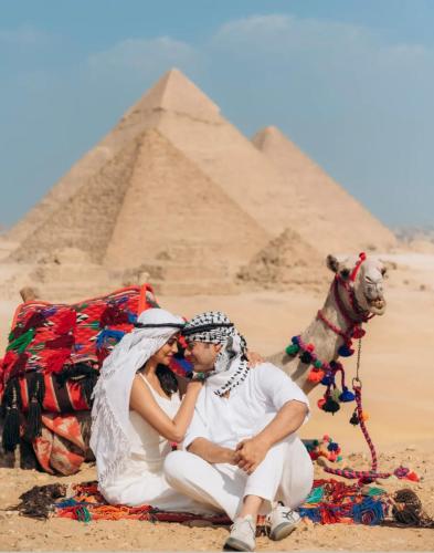 a man and woman sitting in front of the pyramids at Mena Pyramids Hotel in Cairo