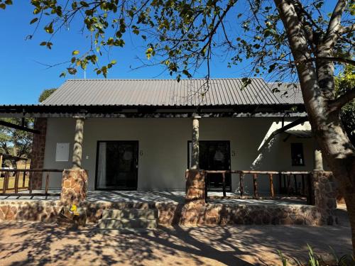 a house with a metal roof and a tree at Welgedacht Lodge in Cullinan