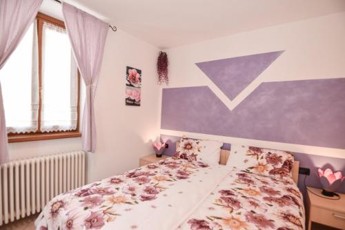 a bedroom with a bed with a floral bedspread at Bed and Breakfast Galet in Ledro