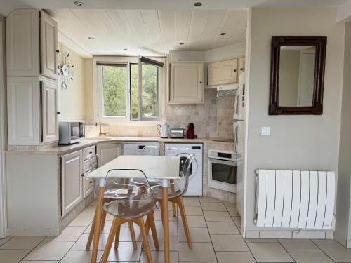 une cuisine avec des armoires blanches et une table et des chaises dans l'établissement Parc de la Trinité La Ciotat, à La Ciotat