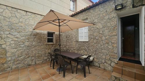 ein Tisch und Stühle mit einem Sonnenschirm auf einer Terrasse in der Unterkunft Casa con encanto amplios jardines al lado de la playa in Caleiro