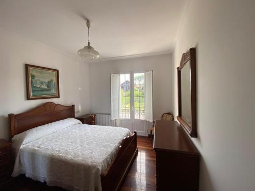 ein Schlafzimmer mit einem Bett, einer Kommode und einem Fenster in der Unterkunft Casa con encanto amplios jardines al lado de la playa in Caleiro