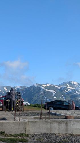a man standing in a parking lot with mountains in the background at House in forest in Gomi