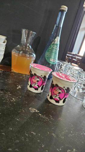 a couple of cups on a table with a bottle at Hôtel de la Poste in Gedinne