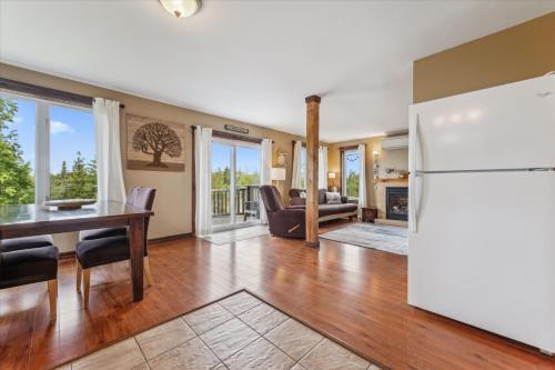 a kitchen and living room with a refrigerator and a table at Dragonfly Cove - Nature-Inspired Lakeside Living in Tobermory