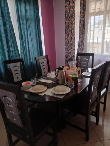 a dining room table with chairs and a table with a tea kettle at Tarangwe Homestay & Hostels in Iringa