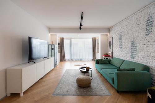 a living room with a green couch and a tv at City One I One Bedroom Apartment near Pipera Plaza Mall in Voluntari