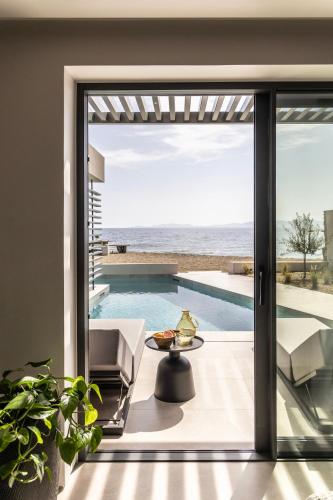 a house with a view of the ocean through a sliding glass door at Orion Tinos Suites in Vrachonisída Chántra