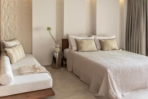 a bedroom with a bed and a chair at Orion Tinos Suites in Vrachonisída Chántra
