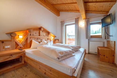 a bedroom with a large bed with a wooden headboard at Apartments DAMONT in Santa Cristina Gherdëina
