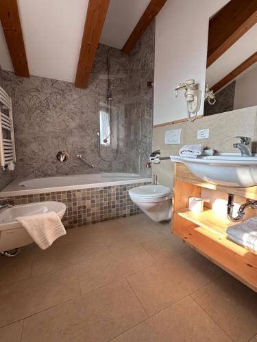 a bathroom with a sink and a tub and a toilet at Apartments DAMONT in Santa Cristina Gherdëina