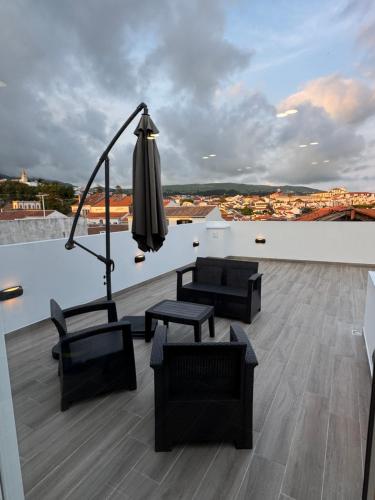 a patio with chairs and an umbrella on a roof at Ponto de vista in Angra do Heroísmo