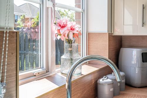 a vase filled with pink flowers sitting in a window at Super Prime Luxury 4 Bedroom Detached Home By Tba in Fife