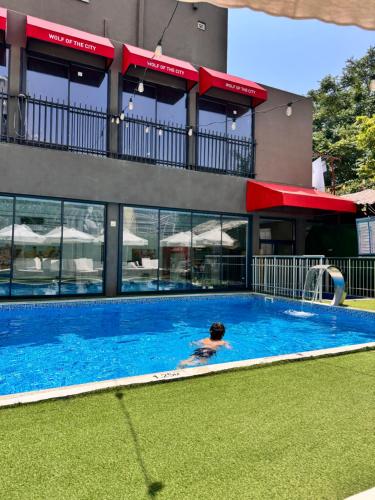 a person in a swimming pool in front of a building at Wolf Of The City Hotel & Spa in Antalya