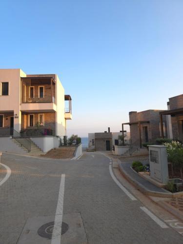 an empty street with buildings and the ocean in the background at Drymadhes Villas & appartments in Himare