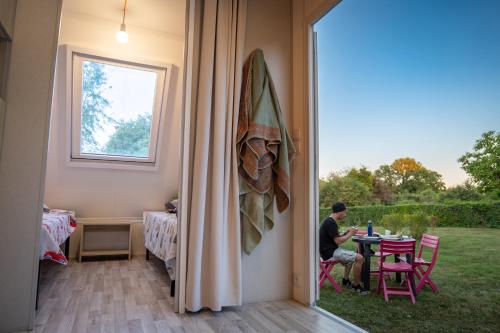 un homme assis à une table dans une maison dans l'établissement Camping Onlycamp La Potinière, à Écueillé