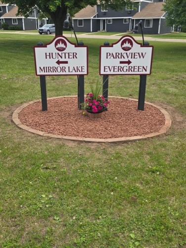 two signs in a circle in a yard with flowers at Tamarack Wisconsin Dells, a Ramada by Wyndham in Wisconsin Dells