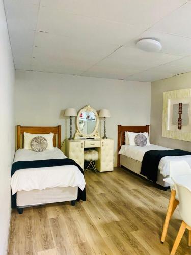 a bedroom with two beds and a desk and a mirror at Boutique at milner guesthouse in Bloemfontein
