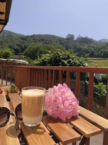 a glass of milk and pink flowers on a wooden table at Casa MARIO y MARIOLA in El Dueso