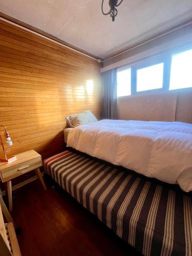 a bedroom with a bed and a bench next to a window at Cálido Bulnes in Punta Arenas