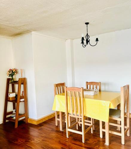 a dining room with a yellow table and chairs at Cálido Bulnes in Punta Arenas