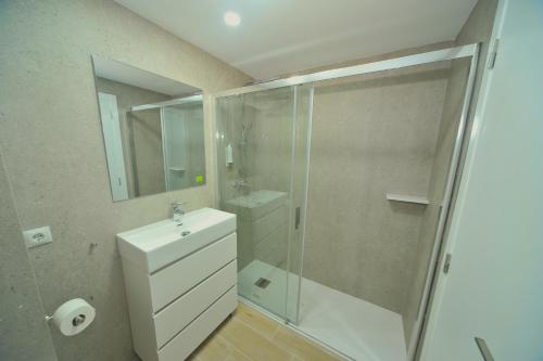 a bathroom with a shower and a sink and a mirror at Orange Park Duplex Atico Premium in Benicàssim
