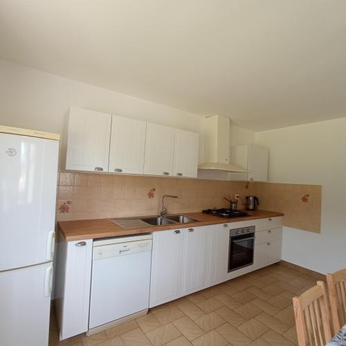 une cuisine avec des armoires blanches, un évier et un réfrigérateur dans l'établissement Escapade verte proche loisirs, à Ploërmel
